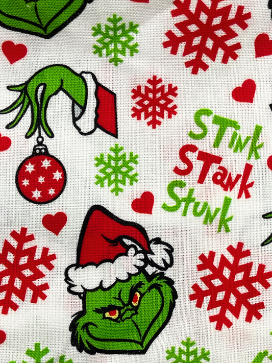 Christmas-themed fabric with Grinch characters, snowflakes, and text on a white background.